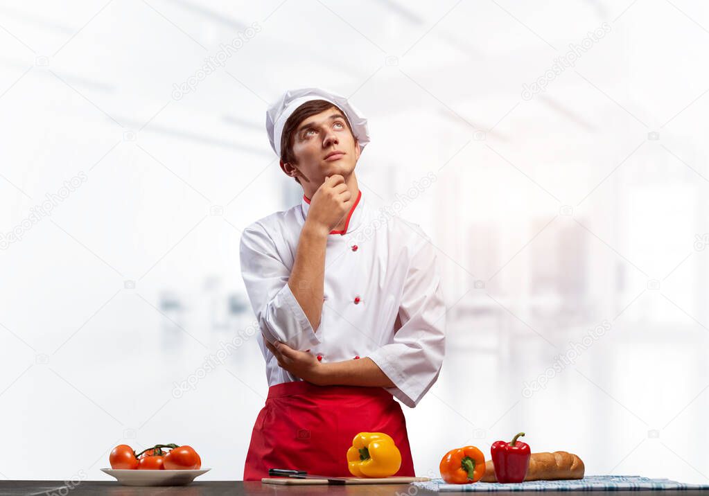 Young male chef standing with folded arms
