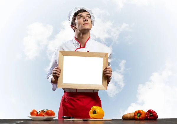 Joven chef masculino de pie cerca de la mesa de cocina —  Fotos de Stock