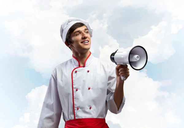 Młody kucharz stojący z megafonem w dłoni — Zdjęcie stockowe