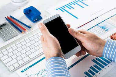 Akıllı telefonlu bir iş adamı, ofiste çalışıyor.