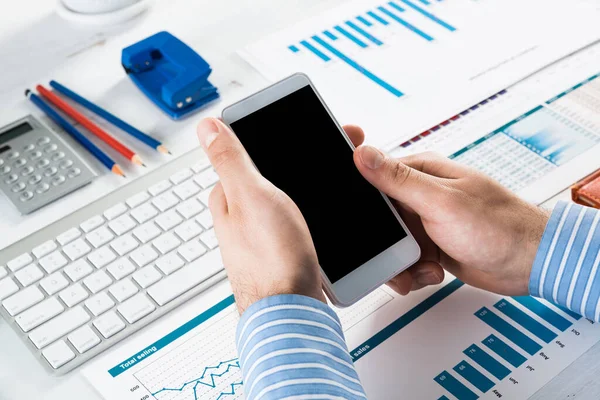 Akıllı telefonlu bir iş adamı, ofiste çalışıyor.
