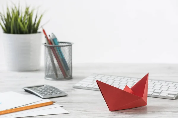 Escritório de madeira com barco de origami vermelho — Fotografia de Stock