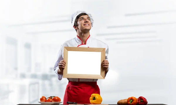 Молодий чоловічий шеф-кухар стоїть біля кухонного столу — стокове фото