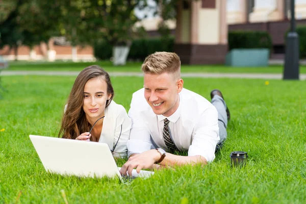 Zakenman en zakenvrouw met een laptop in een stadspark — Stockfoto