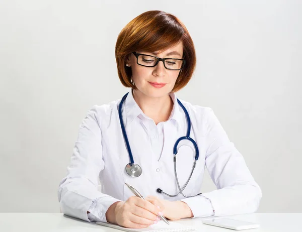 Médico pelirrojo adulto escribiendo en papel en la oficina — Foto de Stock