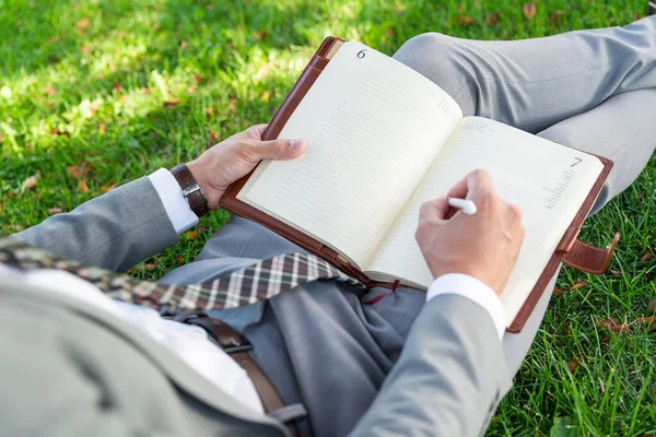 Homme d'affaires dans le parc travaille avec un journal intime — Photo