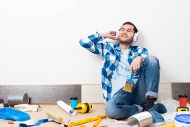 Sakallı adam kulaklıkla müzik dinliyor.