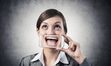 Ağzını akıllı telefonla kapatan kadın.