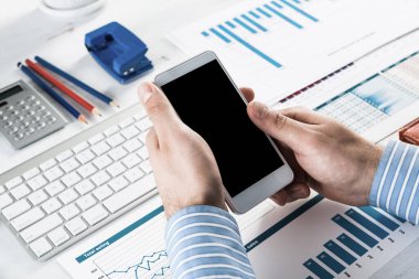 Akıllı telefonlu bir iş adamı, ofiste çalışıyor.