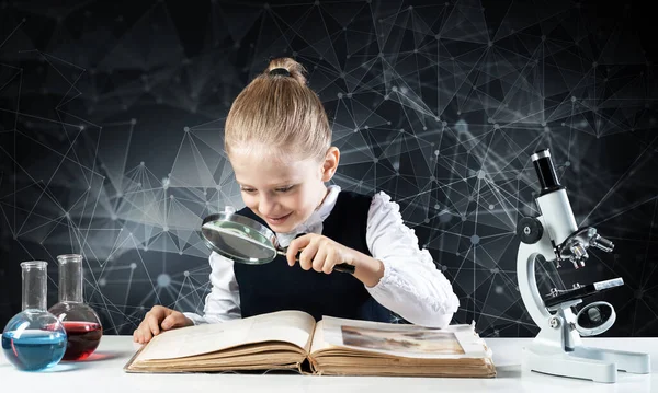 Little girl sitting at desk with magnifier