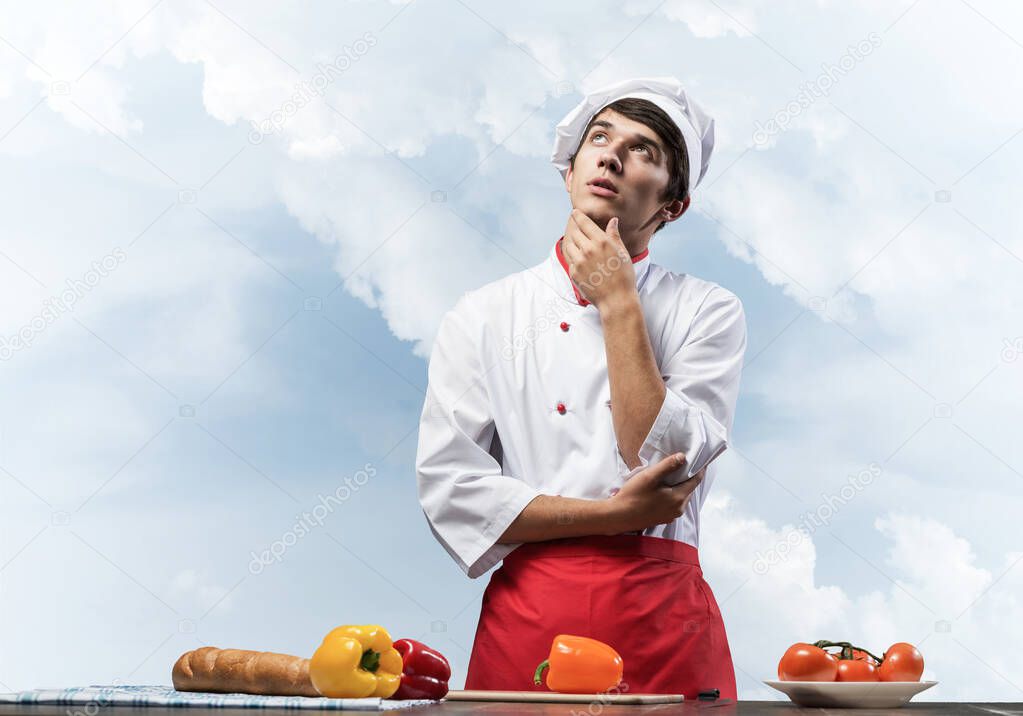 Young male chef standing with folded arms