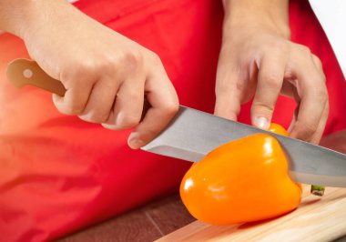 Şefin elleri kırmızı taze biber kesiyor.