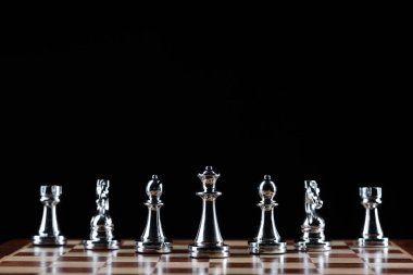 Satranç tahtasının üzerinde duran gümüş satranç figürleri