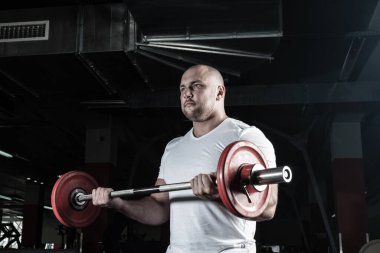 Erkek sporcu halteri kaldırır.