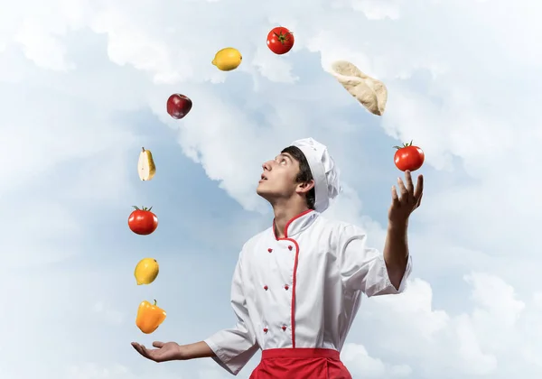 Jovem chef masculino malabarismos com ingredientes alimentares — Fotografia de Stock