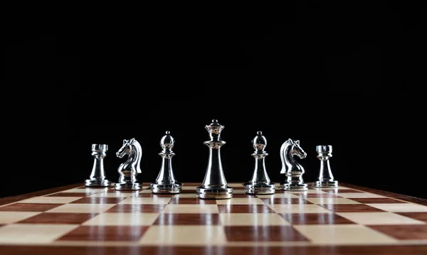 Stříbřité šachové figurky stojící na šachovnici — Stock fotografie