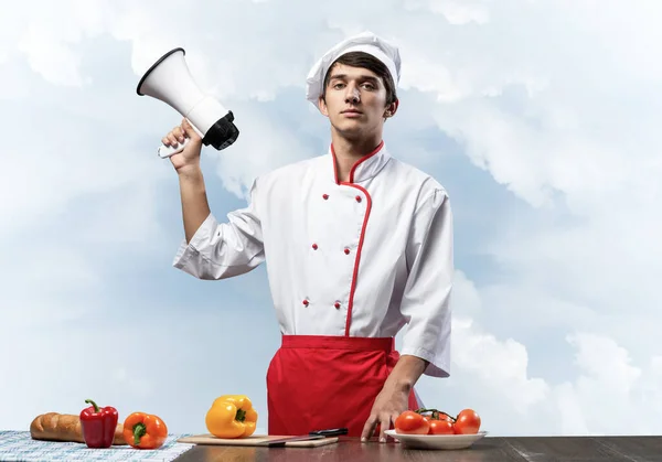 Молодой шеф-повар стоит с мегафоном в руке — стоковое фото
