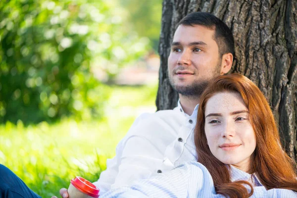 年轻夫妇在树下喝咖啡放松 — 图库照片