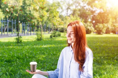 Genç kızıl saçlı kadın Lotus pozunda meditasyon yapıyor.