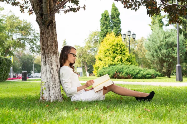 Mooie jonge vrouw met notitieblok in park — Stockfoto