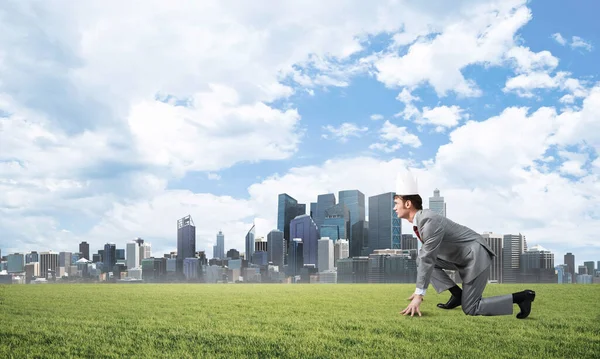 Re uomo d'affari in abito elegante in esecuzione su erba verde e paesaggio urbano moderno sullo sfondo — Foto Stock