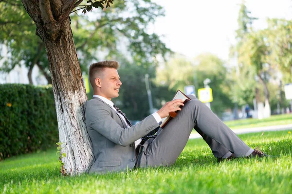 Uomo d'affari nel parco lavora con un diario — Foto Stock