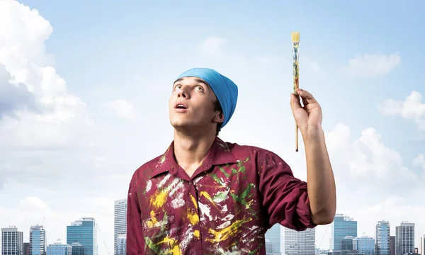 Young painter artist holding paint brush overhead — Stock Photo, Image