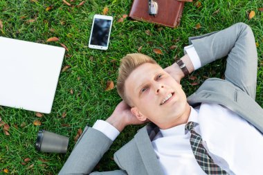 İşadamı çimlerin üzerinde dinleniyor.