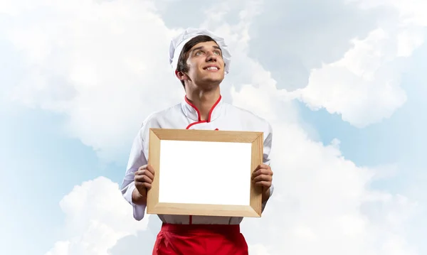 Young male chef holding blank white board — Stock Photo, Image