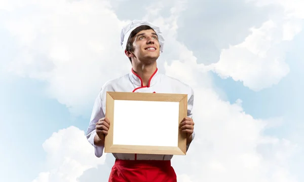 Junger männlicher Koch hält weiße Tafel in der Hand — Stockfoto