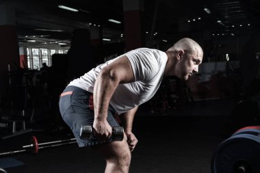 Spor salonunda dambıllarla çarpışan erkek vücut geliştirici.