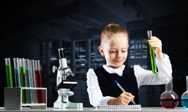 Küçük bilim kadını test tüpünü inceliyor.