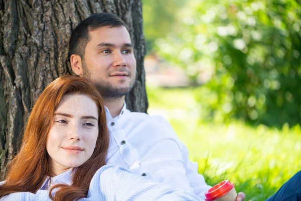 Pareja joven relajándose con café bajo el árbol —  Fotos de Stock