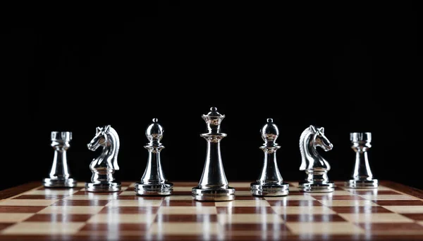 Stříbřité šachové figurky stojící na šachovnici — Stock fotografie
