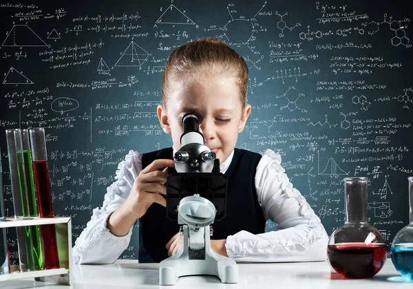 Маленькая девочка-ученый смотрит в микроскоп — стоковое фото
