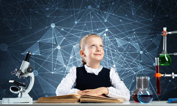 Sorrindo menina sentada na mesa com livro aberto — Fotografia de Stock