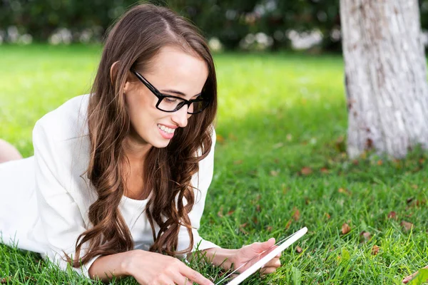 Junge Frau mit digitalem Tablet liegt auf Gras — Stockfoto