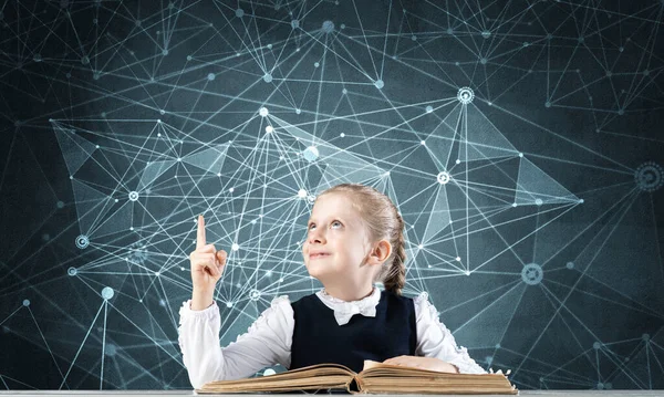 Glimlachend klein meisje aan het bureau met open boek — Stockfoto