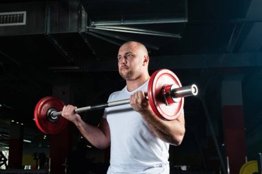 Erkek sporcu halteri kaldırır.