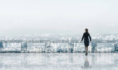 Gökdelenlerin üzerinde gün doğumu ve yeni bir güne bakan iş kadını