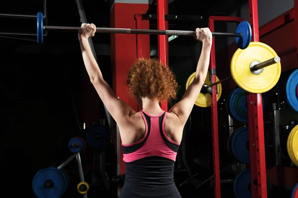 Mujer culturista comprometida con una barra en el gimnasio —  Fotos de Stock