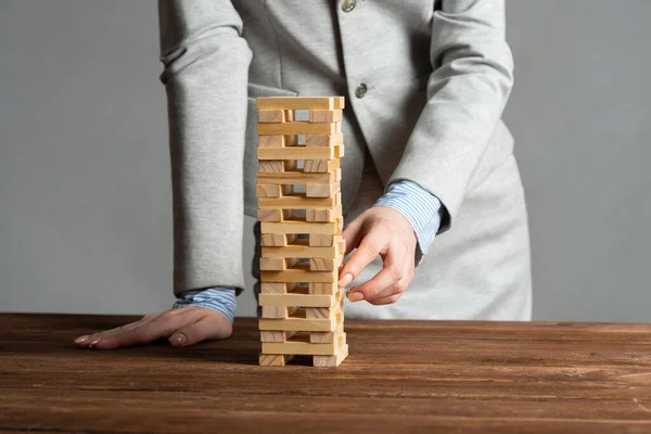 Businesswoman removing wooden block from tower — Stock Photo, Image