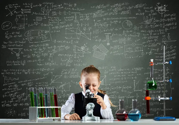 Dívka vědec dívá přes mikroskop — Stock fotografie