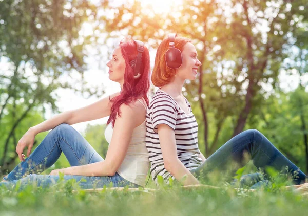 Dos chicas jóvenes en el parque escuchan música. — Foto de Stock