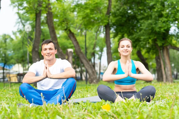 Unga par som gör yoga i parken tillsammans — Stockfoto