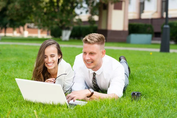 Homme d'affaires et femme d'affaires avec un ordinateur portable dans un parc municipal — Photo