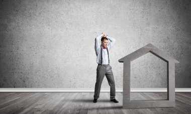 Taştan ev silueti, emlak sigortasının sembolü olarak boş odada.