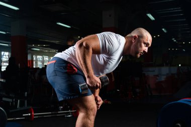 Spor salonunda dambıllarla çarpışan erkek vücut geliştirici.