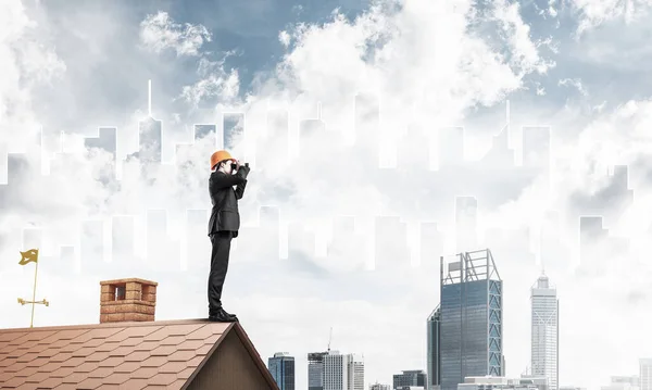 Ingenjör man står på taket och tittar i kikare. Blandat m — Stockfoto