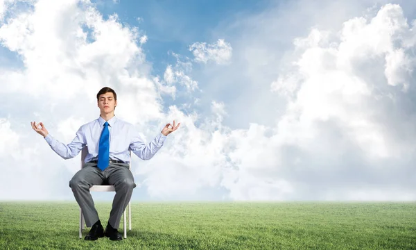 Businessman meditates on office chair Stock Picture